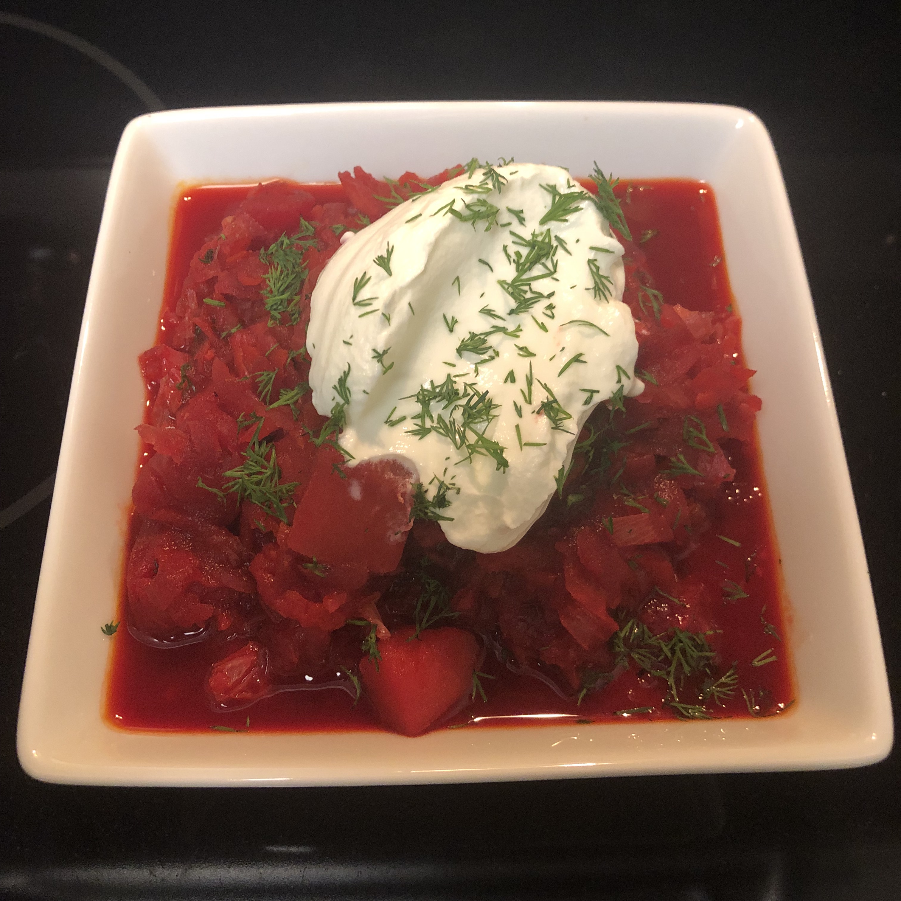 Finished bowl of Borscht, garnished with sour cream and dill