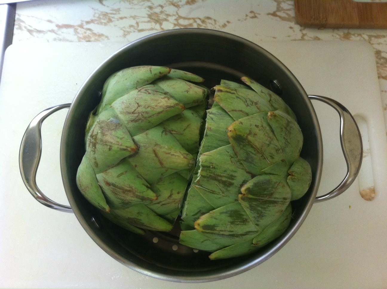 Artichokes in the steamer on their side. This also works facing upward if they fit.
