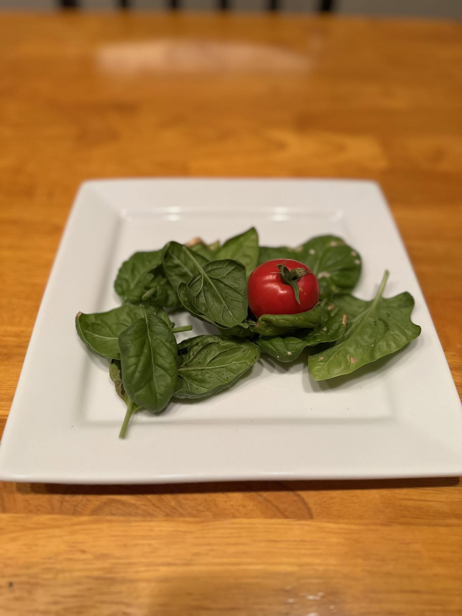plated salad with spinach and a baby tomato